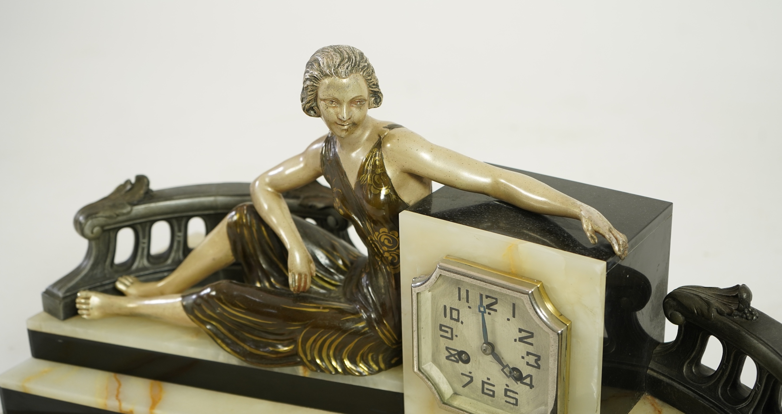 A French Art Deco onyx and patinated spelter clock surmounted with a lady and a black panther on a staircase